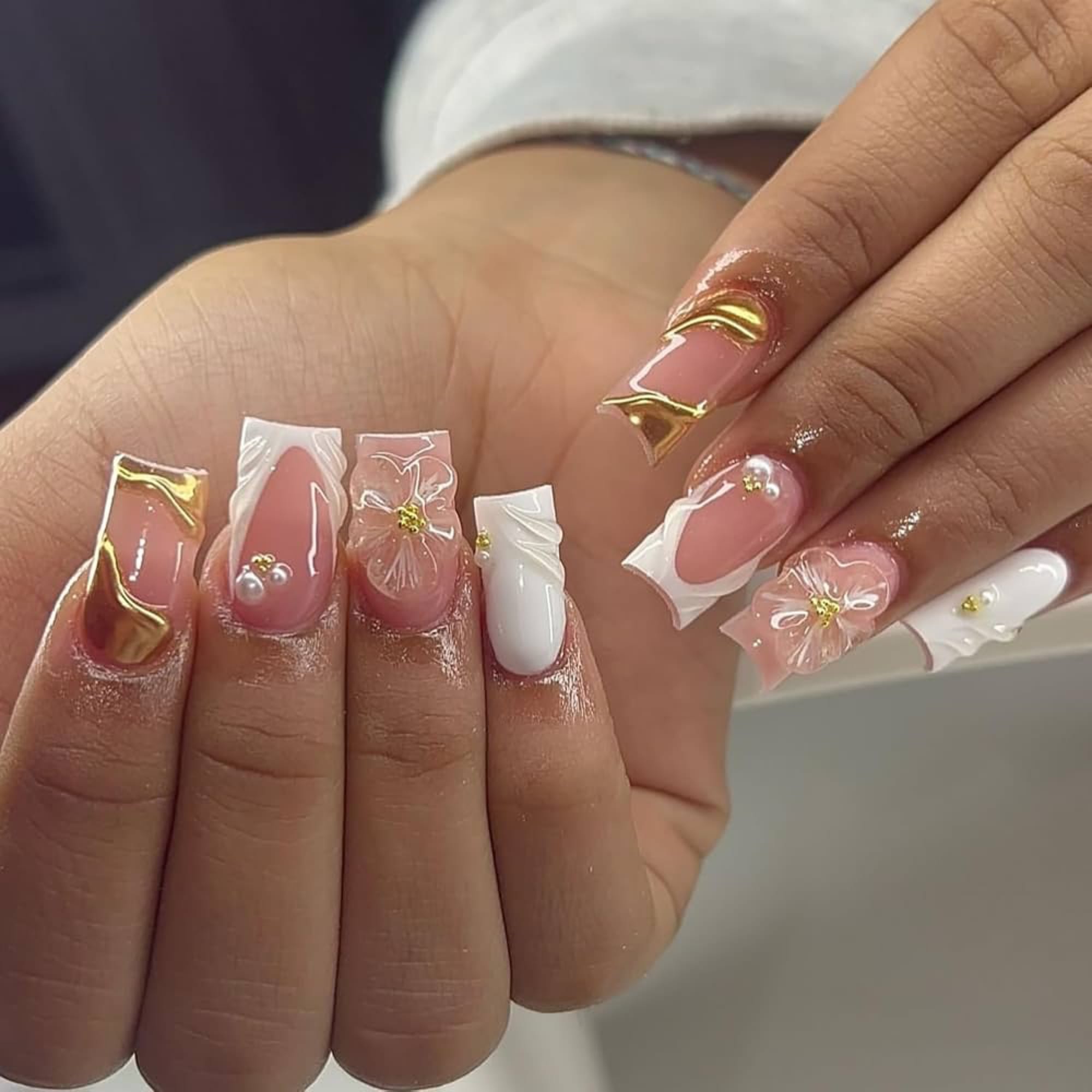 Pink and white acrylic nails with floral art and gold accents